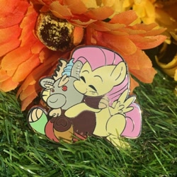 Size: 688x688 | Tagged: safe, artist:3ggmilky, discord, fluttershy, draconequus, pegasus, pony, g4, baby, baby discord, cute, enamel, enamel pin, flower, grass, hug, irl, merchandise, photo, selling