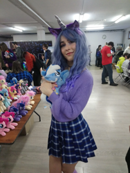 Size: 1622x2160 | Tagged: safe, artist:hysteriana, izzy moonbow, minuette, human, pony, unicorn, g4, g5, blue hair, choker, clothes, convention, cosplay, costume, curly hair, cute, female, festival, hug, irl, irl human, legs, nail polish, photo, plushie, schoolgirl, skirt, solo, sweater, toy