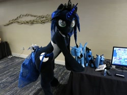 Size: 1758x1318 | Tagged: safe, artist:kolshica, princess luna, alicorn, pony, anthro, g4, bells, butt, clothes, crown, fursuit, glowing, glowing horn, hooves on the table, horn, irl, jewelry, leaning forward, looking at you, photo, plushie, ponysuit, regalia, solo, swimsuit, tail