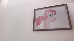 Size: 1280x720 | Tagged: safe, pinkie pie, earth pony, pony, g4, female, hooves, irl, mare, open mouth, paper, photo, picture, picture frame, pointing, smiling, solo, standing, wall