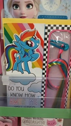 Size: 4000x2250 | Tagged: safe, rainbow dash, pegasus, pony, g4, birthday card, female, in the wild, irl, looking at you, photo, raised hoof, solo, spread wings, walmart, wings