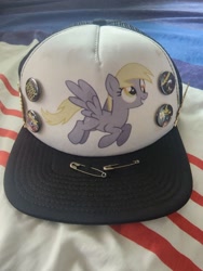 Size: 960x1280 | Tagged: safe, derpy hooves, pegasus, pony, g4, buttons, cap, death metal, hat, irl, merchandise, photo, safety pin, solo