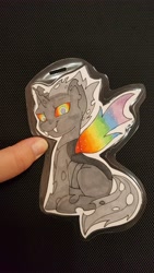 Size: 5312x2988 | Tagged: safe, artist:inkkeystudios, oc, oc only, changeling, pony, badge, colored wings, looking at you, multicolored wings, paper pony, photo, rainbow eyes, rainbow wings, sitting, solo, spread wings, traditional art, wings