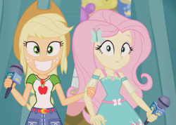 Size: 633x450 | Tagged: safe, screencap, applejack, fluttershy, human, best in show: the pre-show, equestria girls, g4, my little pony equestria girls: better together, belt, big smile, breaking the fourth wall, clothes, collar, cowboy hat, cute, cutie mark on clothes, denim, denim skirt, duo, fluttershy boho dress, geode of fauna, geode of super strength, grin, hairpin, hand on arm, hat, jewelry, just friends, magical geodes, microphone, necklace, shirt, skirt, sleeveless, smiling, stetson, t-shirt, teenager