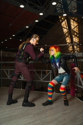 Size: 720x1080 | Tagged: safe, artist:helen the witch, artist:pegasus_fs, rainbow dash, human, g4, arm wrestling, armor, boots, clothes, cosplay, costume, fight, glasses, irl, irl human, jacket, leather, leather jacket, looking at each other, looking at someone, photo, rainbow socks, rubronycon, shadowbolts, shadowbolts costume, shoes, socks, striped socks