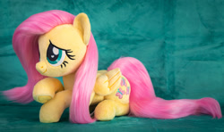 Size: 2182x1288 | Tagged: safe, artist:buttercupbabyppg, fluttershy, pegasus, pony, g4, cute, female, folded wings, irl, lying down, mare, photo, plushie, prone, shyabetes, smiling, solo, wings