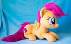 Size: 1914x1195 | Tagged: safe, artist:buttercupbabyppg, scootaloo, pegasus, pony, g4, female, filly, foal, happy, irl, lying down, photo, plushie, prone, smiling, solo, spread wings, wings