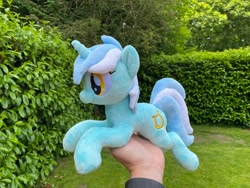 Size: 2048x1536 | Tagged: safe, artist:rtryart, lyra heartstrings, pony, unicorn, g4, female, happy, horn, irl, lying down, mare, outdoors, photo, plushie, prone, smiling, solo