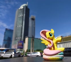 Size: 3453x3000 | Tagged: safe, fluttershy, pegasus, pony, g4, blurry background, city, cityscape, figure, food, high res, indonesia, irl, jakarta, macaron, photo, ponies around the world, pop mart, skyscraper, solo