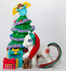 Size: 564x610 | Tagged: safe, photographer:moonbreeze, sweet snowflake, angel, earth pony, pony, g2, christmas, christmas tree, comb, female, filly, foal, holiday, open mouth, photo, plushie, present, raised hoof, solo, teddy bear, toy, tree, unshorn fetlocks