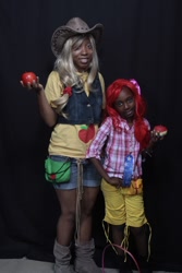 Size: 736x1104 | Tagged: source needed, useless source url, safe, apple bloom, applejack, human, equestria girls, g4, african american, apple, bag, blonde, blonde hair, boots, clothes, cosplay, costume, cowboy boots, cowboy hat, cowgirl, dark skin, denim, denim shorts, duo, flannel shirt, food, hair accessory, hat, irl, irl human, photo, pink ribbon, red hair, ribbon, sassy, shoes, shorts, smiling, zap apple