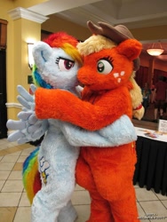 Size: 810x1080 | Tagged: safe, artist:spainfischer, applejack, rainbow dash, earth pony, human, pegasus, pony, anthro, g4, 2011, clothes, convention, cosplay, costume, cowboy hat, embrace, female, fursuit, hat, hug, hugging a pony, irl, irl human, megaplex, photo, ponysuit, pose, ship:appledash, shipping, smiling, smirk, spread wings, suit, tail, wings