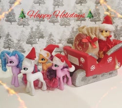 Size: 1080x959 | Tagged: safe, artist:heart k art, hitch trailblazer, izzy moonbow, pipp petals, sunny starscout, zipp storm, earth pony, pegasus, pony, unicorn, series:heart k art g5 advent calendar, g5, advent calendar, christmas, female, hat, holiday, horn, irl, male, mane five, mare, photo, santa hat, sleigh, stallion, toy