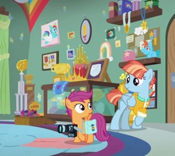 Size: 804x720 | Tagged: safe, edit, edited screencap, screencap, rainbow dash, scootaloo, windy whistles, pegasus, pony, g4, parental glideance, bag, camera, clothes, cropped, dashmentos, diaper, female, filly, foal, freckles, jacket, looking at each other, looking at someone, mare, rainbow dash rug, saddle bag, smiling, trophy, trophy room