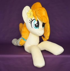 Size: 1296x1312 | Tagged: safe, artist:egalgay, pear butter, earth pony, pony, g4, female, flower, flower in hair, happy, irl, lying down, mare, photo, plushie, prone, smiling, solo, sploot