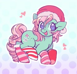 Size: 1627x1566 | Tagged: safe, artist:horseyuris, minty, earth pony, pony, g3, blushing, cheeks, christmas, clothes, curly mane, curly tail, gradient background, green coat, happy, hat, heart, holiday, looking at you, pink mane, polka dot background, purple eyes, santa hat, smiling, smiling at you, socks, solo, striped socks, tail
