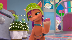 Size: 1276x720 | Tagged: safe, screencap, sunny starscout, earth pony, pony, g5, my little pony: make your mark, my little pony: make your mark chapter 3, winter wishday, spoiler:g5, spoiler:winter wishday, belly, cap, coat markings, cookie, crystal brighthouse, depth of field, door, eyebrows, female, food, grin, hat, hoof hold, indoors, lidded eyes, mane stripe sunny, mare, peruvian hat, raised hoof, smiling, socks (coat markings), solo, string lights, sunny's bag, unshorn fetlocks