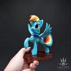 Size: 2560x2560 | Tagged: safe, alternate angle, alternate version, artist:lakterra, rainbow dash, human, pegasus, pony, g4, craft, female, figurine, hand, holding a pony, irl, irl human, looking up, mare, photo, polymer clay, raised hoof, signature, smiling, solo, spread wings, stand, tail, wings
