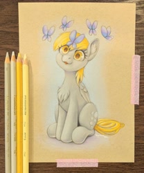 Size: 2114x2537 | Tagged: safe, artist:taytinabelle, derpy hooves, butterfly, pegasus, pony, g4, :3, :p, chest fluff, colored pencil drawing, colored pencils, cute, ear fluff, female, folded wings, irl, looking at you, mare, photo, simple background, sitting, smiling, solo, tongue out, traditional art, wings