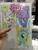 Size: 768x1024 | Tagged: safe, artist:andy price, artist:thom zahler, artist:tony fleecs, lyra heartstrings, mayor mare, trixie, earth pony, pony, unicorn, g4, c2e2, c2e2 2014, clothes, collaboration, female, glasses, hat, horn, irl, mare, my little pony logo, photo, sparkles, traditional art, trixie's hat