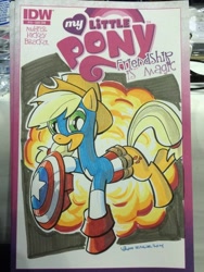 Size: 768x1024 | Tagged: safe, artist:thom zahler, idw, applejack, earth pony, pony, g4, spoiler:comic13, 2014, applejack's hat, captain america, clothes, comic cover, commission, cosplay, costume, cover, cover art, cowboy hat, crossover, explosion, female, hat, irl, mare, marvel, my little pony logo, new york comic con, new york comic con 2014, open mouth, open smile, photo, raised hoof, raised leg, shield, signature, smiling, solo, tail, traditional art