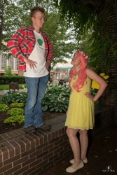 Size: 684x1024 | Tagged: safe, big macintosh, fluttershy, human, g4, 2015, brick wall, clothes, cosplay, costume, cutie mark on clothes, denim, dress, duo, duo male and female, female, floral head wreath, flower, hand on hip, holding hands, irl, irl human, jeans, looking at each other, looking at someone, male, pants, photo, plaid shirt, ship:fluttermac, shipping, shirt, shoes, straight, t-shirt, tree, wig, wings