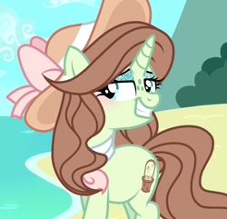 Size: 1266x1220 | Tagged: safe, artist:cstrawberrymilk, oc, oc only, oc:earliglow basket, pony, unicorn, alternate hairstyle, beach, blue sky, blushing, brown mane, brown tail, day, eyelashes, eyeshadow, female, female oc, freckles, glitter, green coat, green eyes, green eyeshadow, hat, horn, lidded eyes, long mane, long tail, looking back, makeup, mare, mare oc, neckerchief, ocean, outdoors, sand, screencap background, sky, smiling, solo, sparkly eyeshadow, sun hat, tail, three quarter view, turned head, unicorn horn, unicorn oc, water, wavy mane, wavy tail